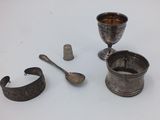 a silver cup, a spoon, and a thimble on a table