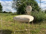 two chairs and a table in a field with a bird cage