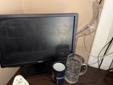 a television sitting on top of a wooden desk next to a cup of water