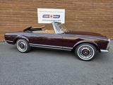 an image of a maroon convertible car parked in front of a building