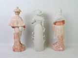 three ceramic figurines of women with hats and gowns on a white background
