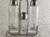 three salt and pepper shakers on a metal holder
