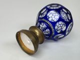 a blue and white glass vase with a gold base