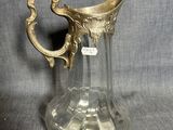 un pichet ancien en verre avec une anse dorée sur fond gris