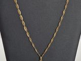 un collier en or avec une croix et une chaîne, posé sur un mannequin