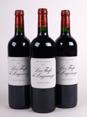 trois bouteilles de vin rouge posées l'une à côté de l'autre sur une surface blanche
