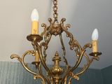 un lustre en or auquel sont suspendues trois bougies