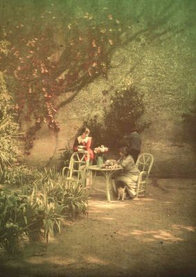 une femme assise à une table dans un jardin