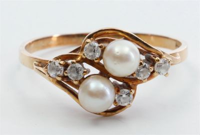 une image représentant une bague en or ornée de deux perles et de diamants