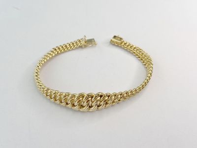 gros plan d'un bracelet en or sur une surface blanche