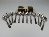 six cuillères en argent et une boîte de cuillères en argent posées sur une table