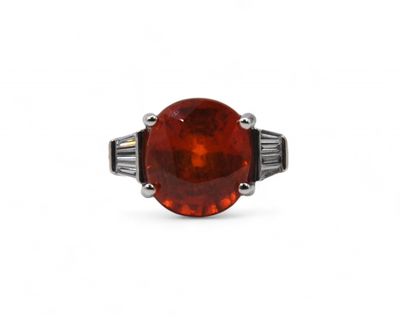 a red stone ring with a baguet of diamonds in the center