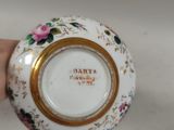 a small white bowl with a gold rim and flowers on it