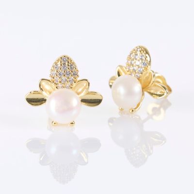 a pair of pearl and diamond earrings on a white surface