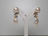une paire de boucles d'oreilles en perles et saphirs exposée sur un présentoir blanc