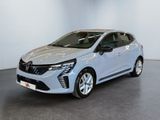 Une voiture argentée est garée dans une pièce aux murs blancs.