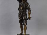 a bronze statue of a man with a basket on his head and a hat on his head