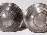 pair of silver plated bowls on a white surface with a white background