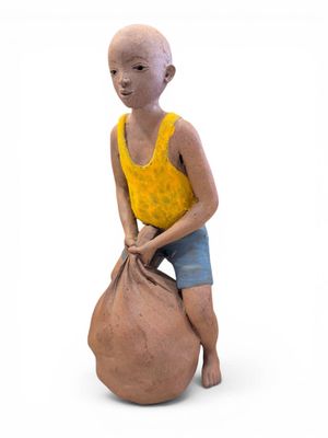 une figurine en argile représentant un garçon assis sur un sac