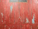 a red door with a window and a window grill on it