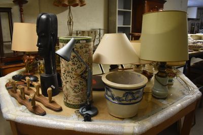 une table sur laquelle se trouvent une lampe, un vase, une autre lampe et d'autres objets