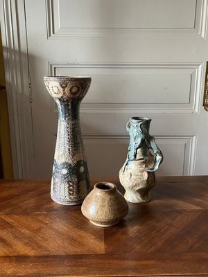 trois vases posés sur une table en bois devant une porte