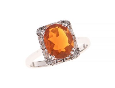 un gros plan d'une bague ornée d'une pierre orange entourée de diamants