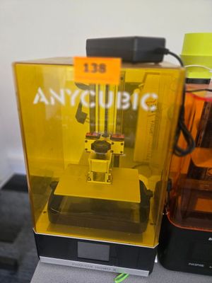 une imprimante 3D jaune posée sur une table, à côté d'une bouteille d'eau