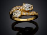 un gros plan d'une bague en or sertie de deux diamants sur une surface noire