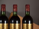 three bottles of red wine sit on a table next to a wooden box