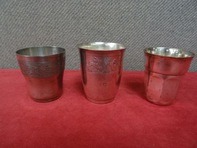 trois coupes en argent posées sur une nappe rouge