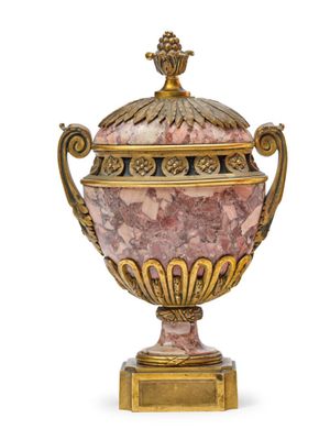 a pink and gold vase with a lid on a stand