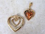 deux pendentifs en forme de cœur en or posés sur une surface en marbre