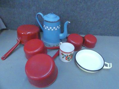 une théière bleue et des casseroles et poêles rouges posées sur une table