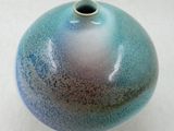 un vase bleu et violet posé sur une surface blanche
