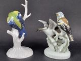 two figurines of birds sitting on a tree branch