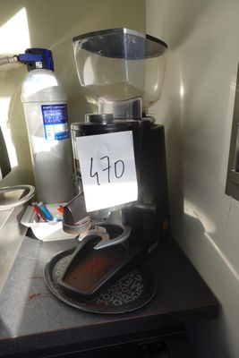 une cafetière posée sur un plan de travail, sur laquelle est accrochée une pancarte