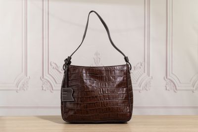a brown purse sitting on top of a wooden table next to a wall