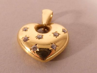 a gold heart shaped pendant with diamonds on it