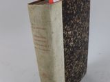 un livre portant une étiquette rouge, posé sur une surface blanche
