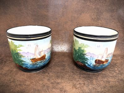 two cups with boats painted on them sitting on a brown surface