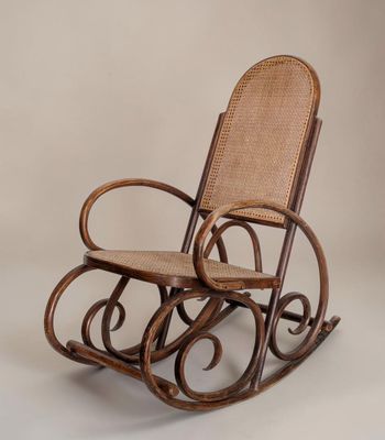 un fauteuil à bascule avec une assise en osier sur fond blanc