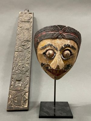 an image of a wooden mask next to a ruler on a table