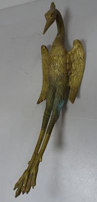 statue en bronze représentant un oiseau posé sur une surface blanche, avec un fond blanc