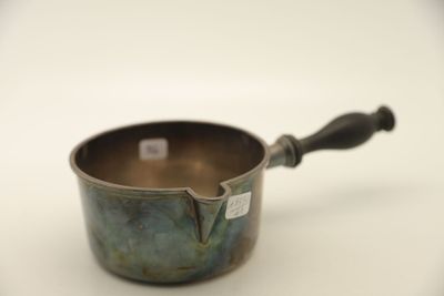 une petite casserole en métal avec une poignée, posée sur une surface blanche