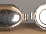 two silver dishes sitting on a wooden table