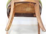 a teddy bear sitting on a wooden chair with a green seat