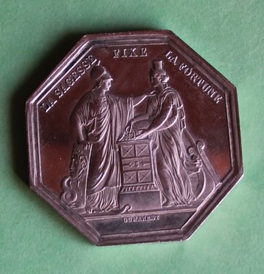 an antique silver coin with a picture of two people on it