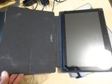 a person holding a tablet and a laptop on a table