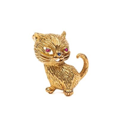 une image représentant une broche en forme de chat en or aux yeux rouges